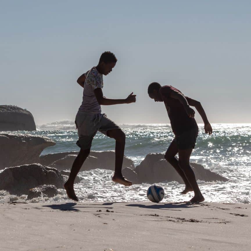 kids playing football on beach